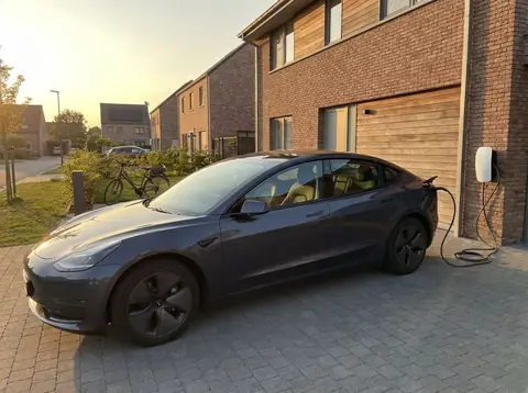 Voiture electrique branchee a une borne de recharge devant une maison